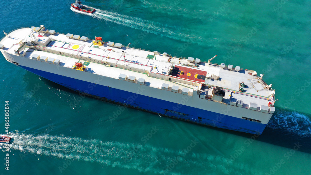 Aerial drone photo of large car carrier ro ro vessel guided by tug boats to anchor to Mediterranean car terminal port