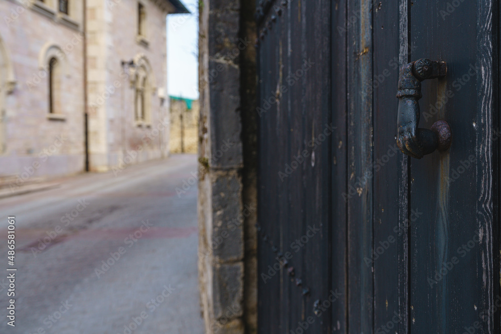 Old knocker in the shape of a hand in an old gate in the town of Llanes, Asturias, Spain Old knocker in the shape of a hand in an old gate in the town of Llanes, Asturias, Spain