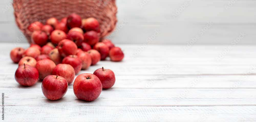 jabłka w wiklinowym koszu na rustykalnym tle białych desek - obrazy, fototapety, plakaty 