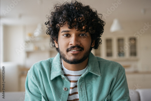Portrait of smiling Indian student listening online lesson sitting at home. Handsome asian man having video call, communication online. Video conference concept