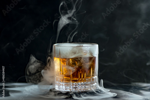 A classic cocktail in a tumbler surrounded by smoke. 