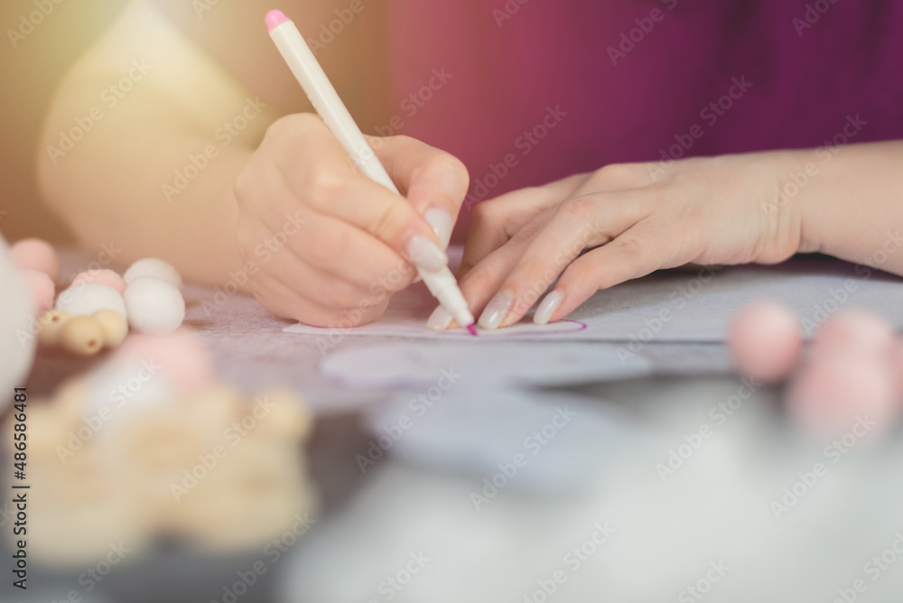 Women's hands make a pattern on a white felt. Step-by-step instructions for creating hand-made products from felt. step 1.Mobile in the crib Women's hands make a pattern on a white felt. Step-by-step instructions for creating hand-made products from felt. step 1.Mobile in the crib