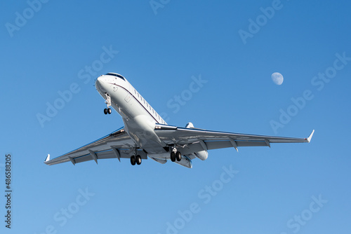business jet on final approach with the moon in the background