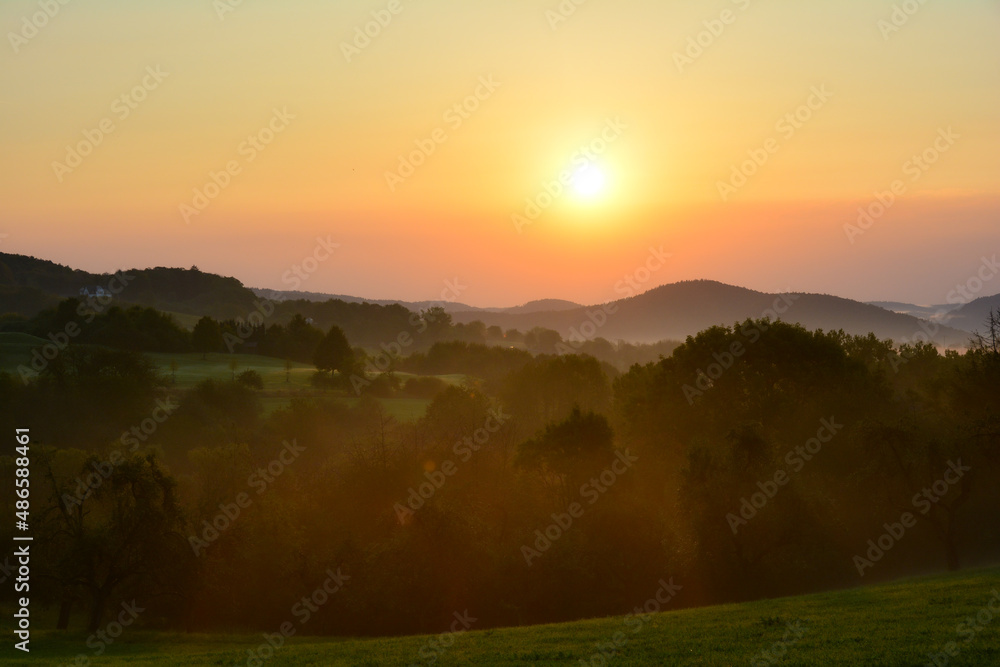 Sun rises over a landscape with morning fog in Germany Sun rises over a landscape with morning fog in Germany