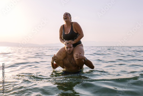 Man gives piggyback ride to his friend in water photo