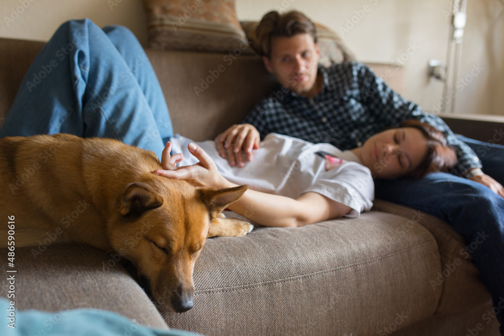a couple with a dog on the couch
a couple with a dog on the couch