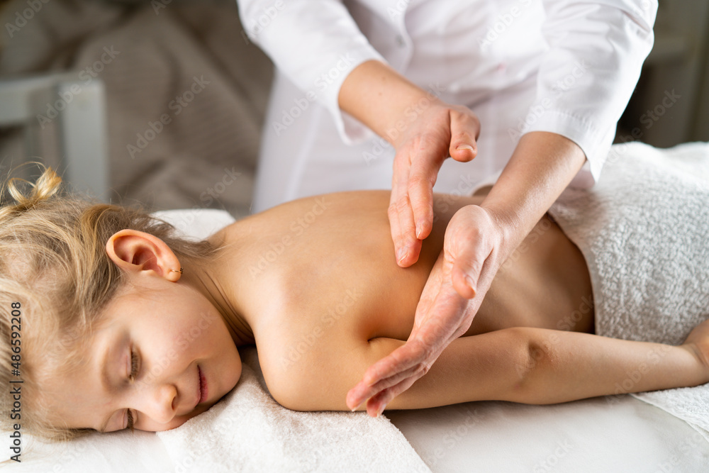 a woman gives a massage to a little girl, children's massage, prevention of scoliosis, osteopathy a woman gives a massage to a little girl, children's massage, prevention of scoliosis, osteopathy