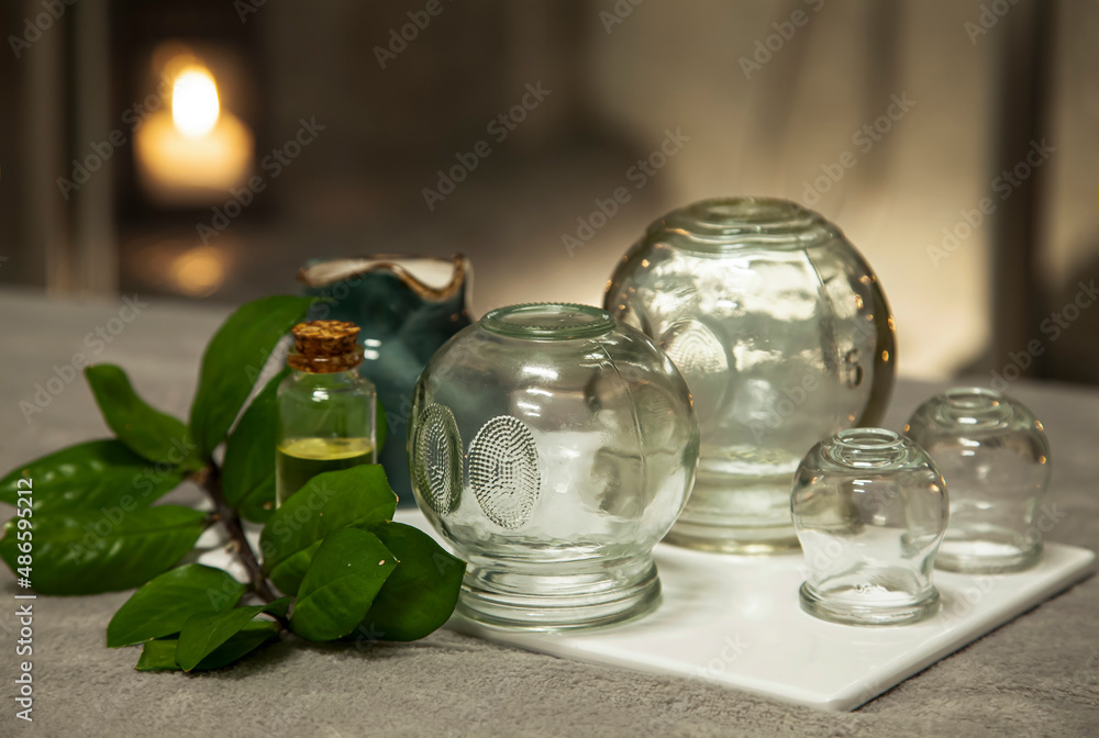 Cupping  therapy glass cups  at wellnes massage center, natural skin therapy for meridians of the body, suction stimulating flow of energy. - obrazy, fototapety, plakaty 