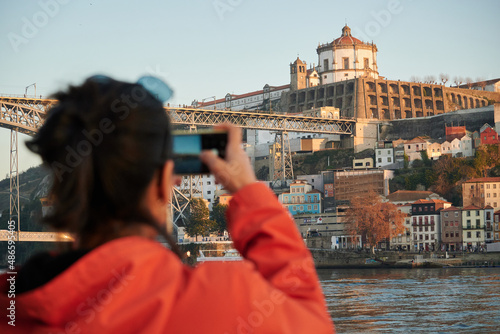 A beautiful shot of a Spanish girl taking a photo of a cityscape in porto