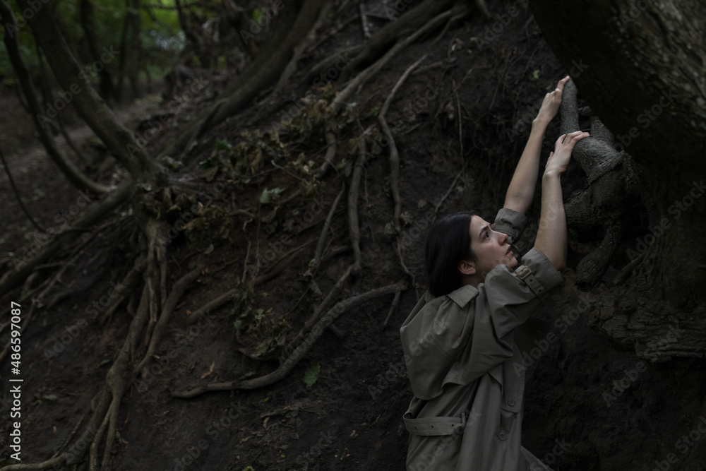 a girl climbs up the roots of a tree
a girl climbs up the roots of a tree