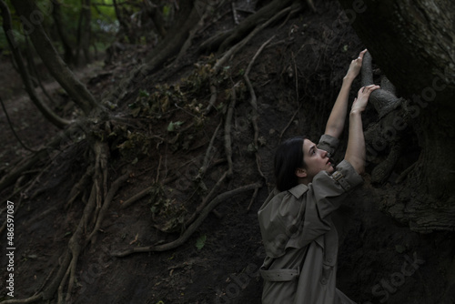 a girl climbs up the roots of a tree
 photo