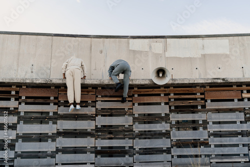 Friends climbing a wall helping each other photo