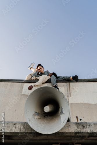 Friends laying down on top of wall next to megaphone photo