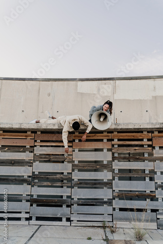 Woman talking on megaphone on top of wall photo