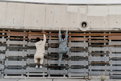 Friends climbing a wall helping each other photo