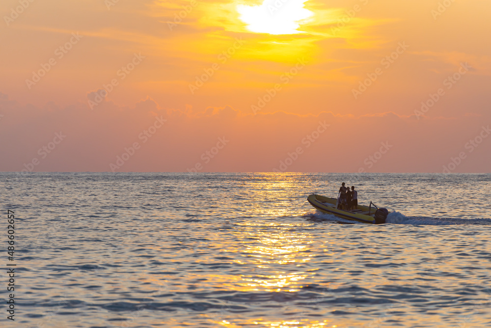 Motor boat at sea. A yellow rubber boat cleaves the calm sea in the sunset light.