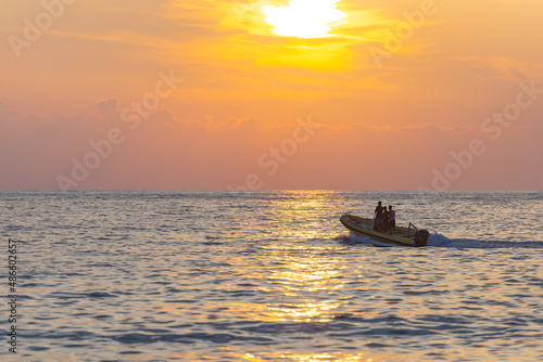Motor boat at sea. A yellow rubber boat cleaves the calm sea in the sunset light. © Михаил Шаповалов