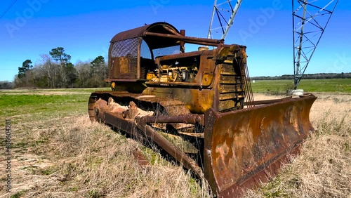 Corner distant pan Old antique rusted vintage abandoned tractor on a farm inoperable photo