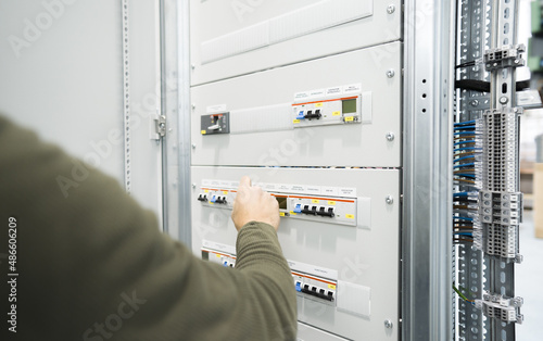 electrician operating circuit breaker on industrial electrical panel