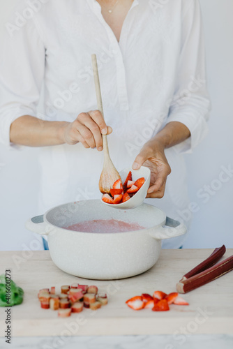 Woman adding strawberries rhubarb for drink