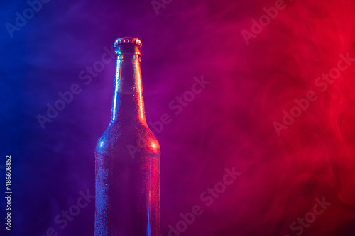 Glass bottle of beer in blue pink mist