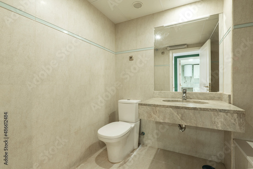 Bathroom decorated with cream colored faux marble tiles and marble veined sink countertop with square frameless mirror in vacation rental home