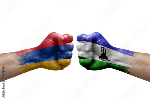 Two hands punch to each others on white background. Country flags painted fists, conflict crisis concept between armenia and lesotho