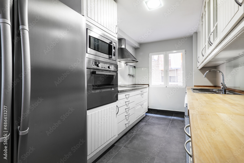 kitchen with wooden furniture and metallic gray appliances with a window in the background kitchen with wooden furniture and metallic gray appliances with a window in the background