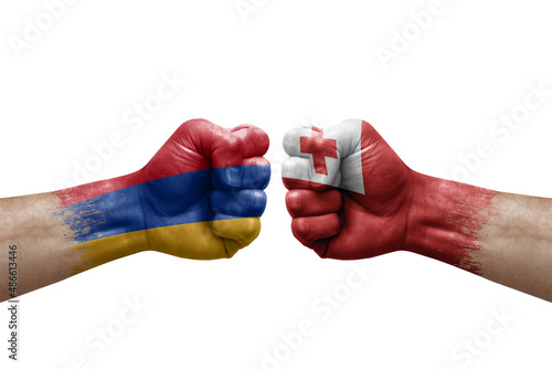 Two hands punch to each others on white background. Country flags painted fists, conflict crisis concept between armenia and tonga