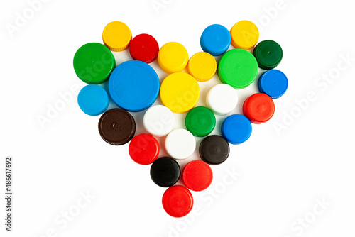 Colored screw caps for plastic bottles used to seal plastic bottles on a white background. Used bottle caps in the shape of a heart collected for plastic recycling. Separate waste sorting. © Andrii A
