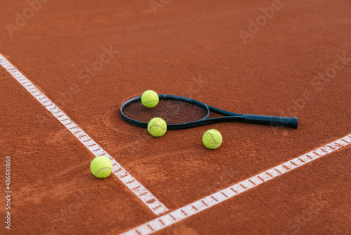 Tennis racquet on a court with tennis balls