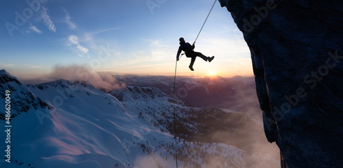 Vászonkép Adult adventurous man rappelling down a rocky cliff