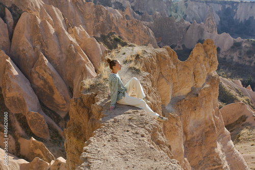 a woman is sitting on a cliff