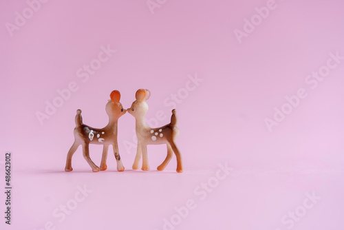 pareja de ciervos o venados miniatura dándose un beso sobre fondo rosa con espacio para texto photo