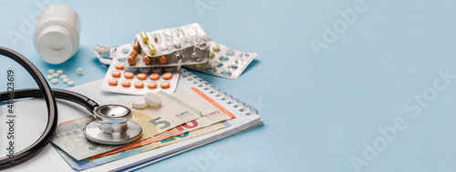Cost of medicinal products and treatment concept. Copy space. Cost of health care with EURO bank notes, stethoscope and medicaments. Price of medicine. Medical expenses. EURO small bills cash money. 