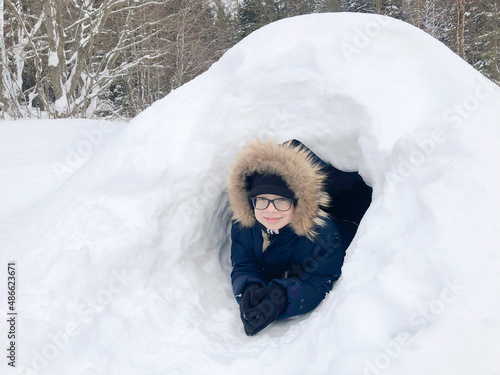 A joyful child with glasses in an Eskimo dwelling - an igloo, close-up. Winter fun.