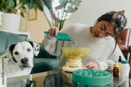 Woman measuring dog food with scale photo