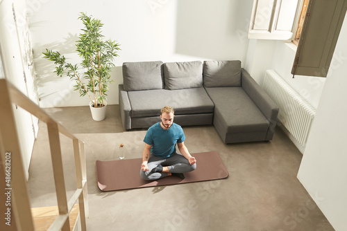 Young man at home, doing yoga photo