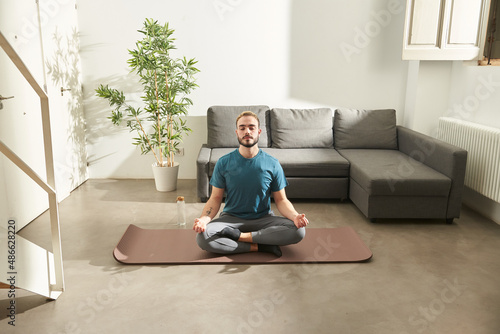 Young man at home, doing yoga photo