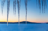 Icicles in frozen Winter landscape with lake 