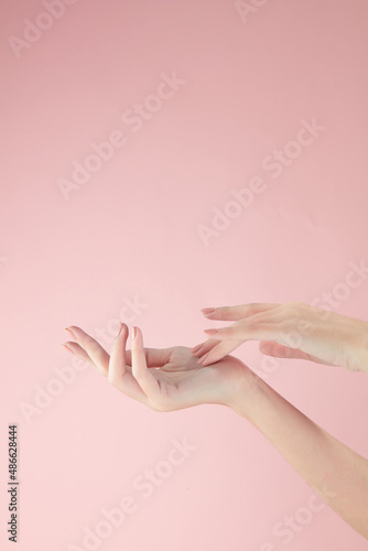 Hand model using cosmetic with a pink background for cosmetic advertising   front view 
