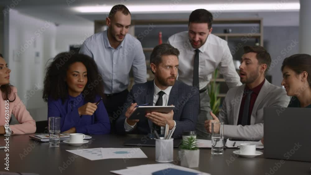 Multiethnic team using tablet device analyzing finance on office conference. Multiethnic team using tablet device analyzing finance on office conference.