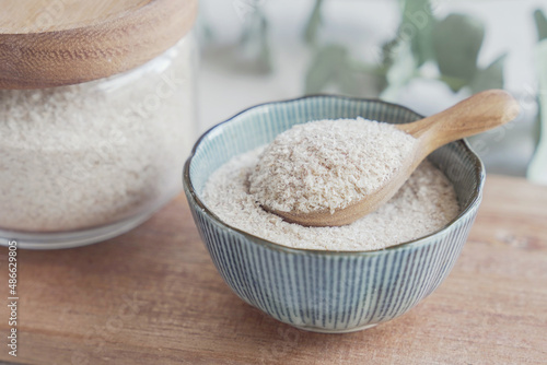 Fotografi Psyllium husk in wooden spoon and bowl on wooden plate, superfood fiber prebioti