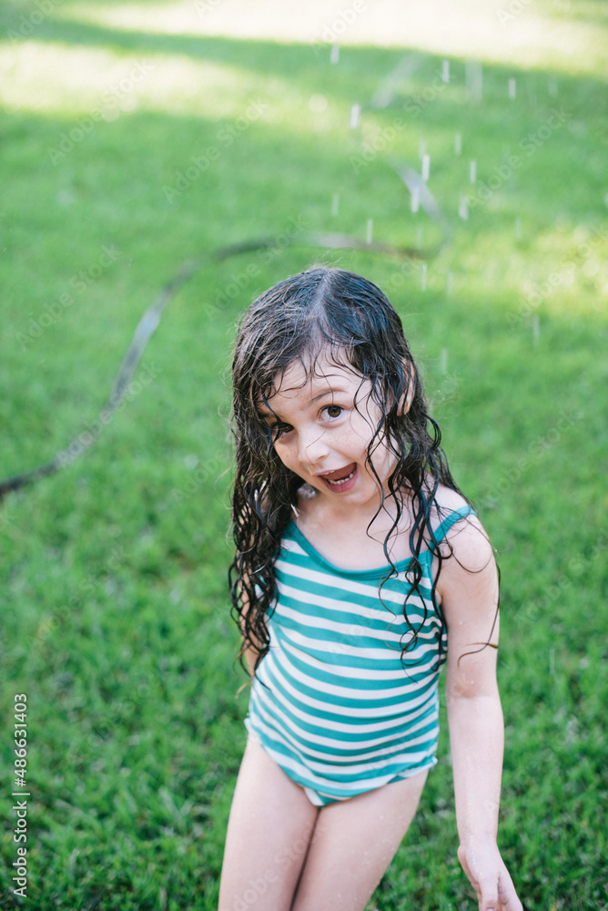 Young siblings playing in a sprinkler Young siblings playing in a sprinkler