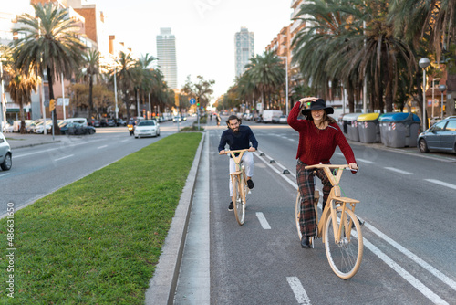 Positive friends riding wooden bicycles in city center photo