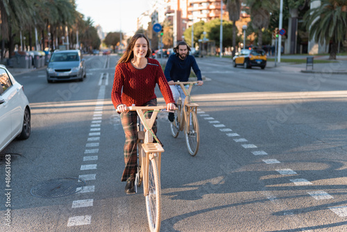 Positive friends riding natural bicycles on asphalt road