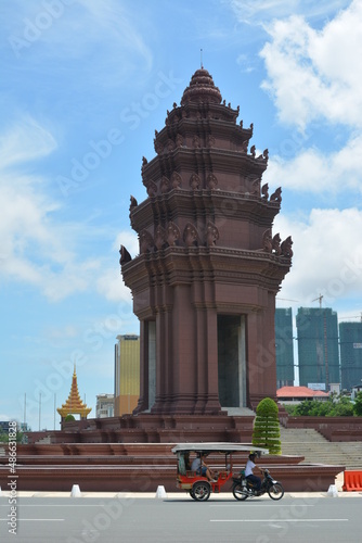 Combination of historic and modern structures in the panorama view of Phnom Penh with an iconic tuk-tuk vehicle in the foreground