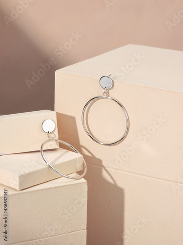 Large ring shaped earrings isolated on beige podium photo