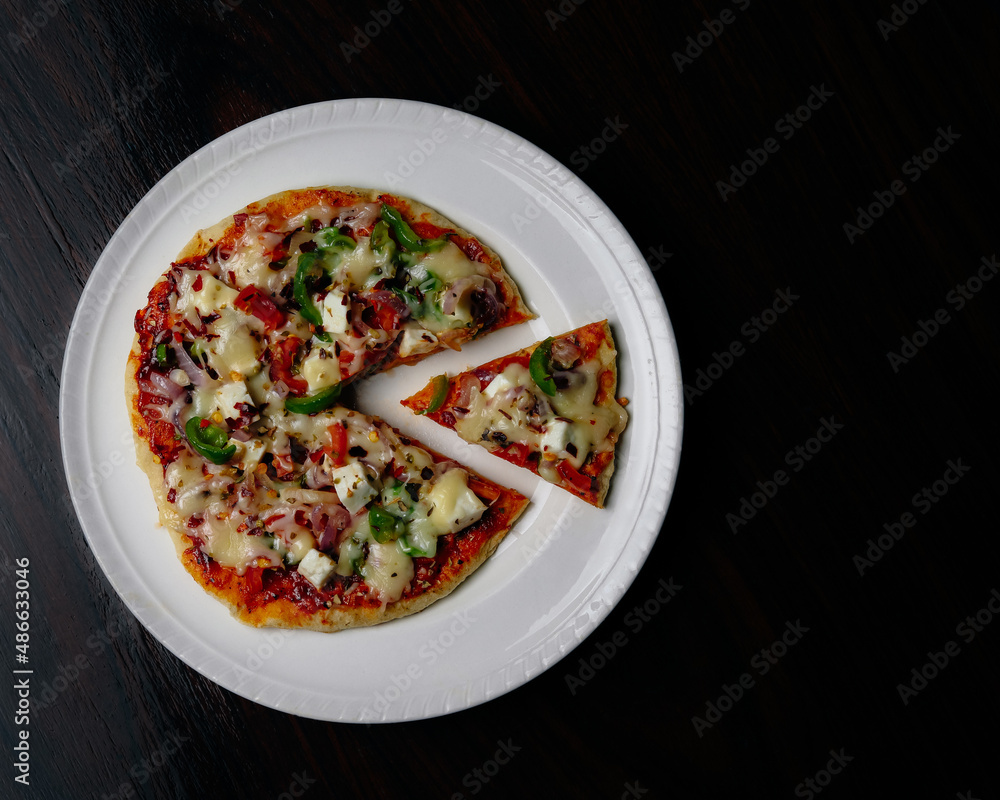 Fresh pan vegetable pizza served on white platter with a black background