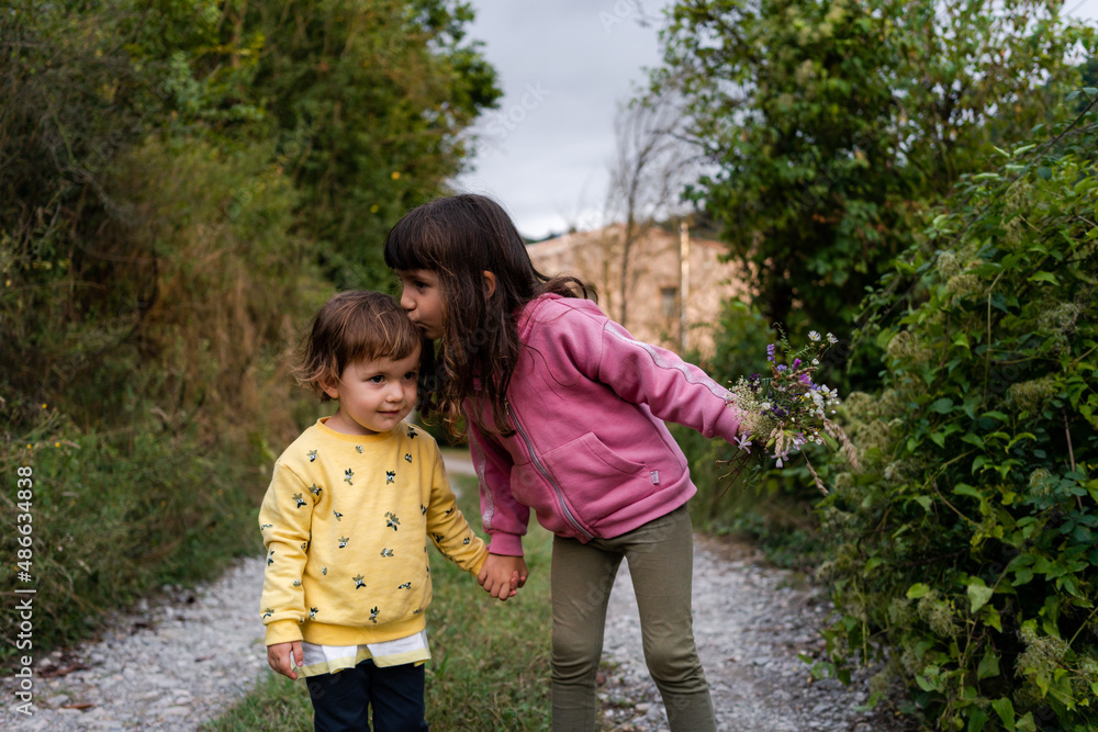 Two daughters kissing outdoors